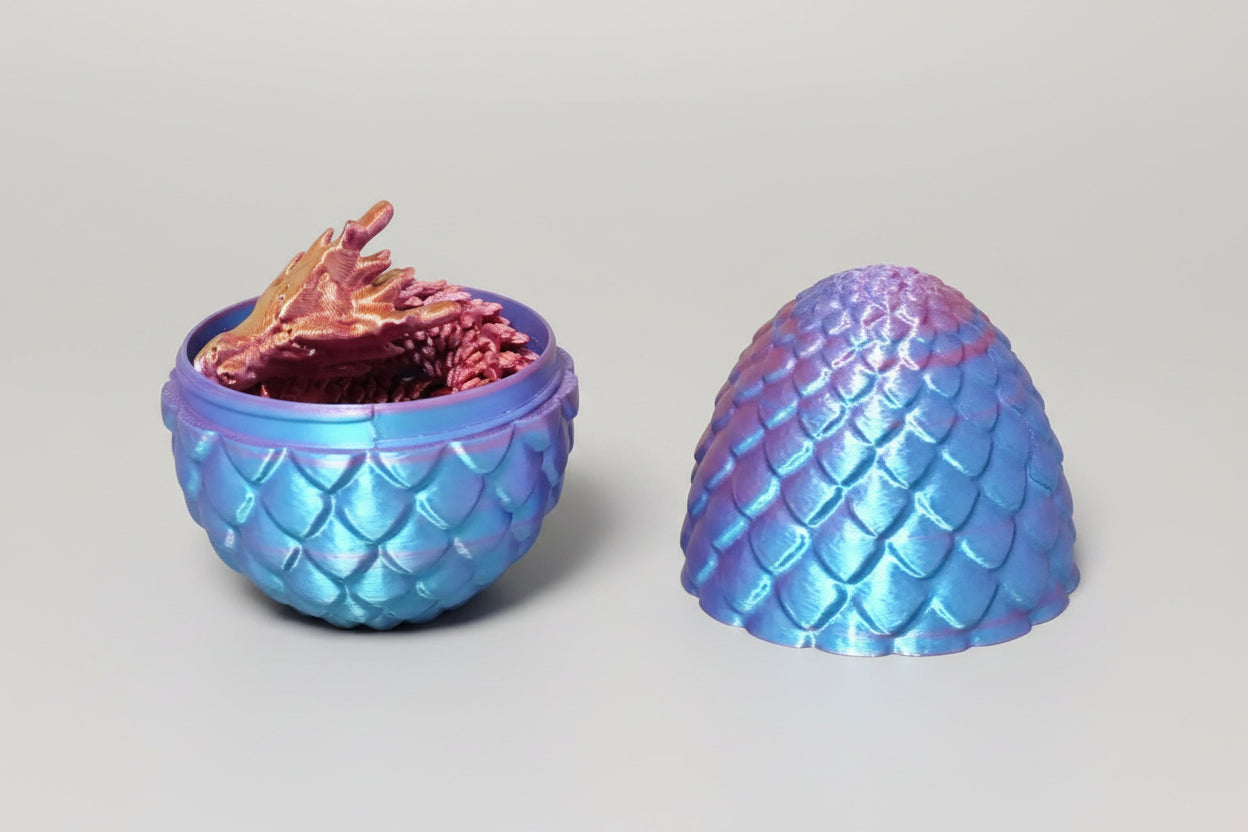 Open multicolor drakenei met schubstructuur en los verkrijgbaar 3D-geprint draakje als sfeerbeeld.