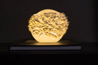 Atoll mini sfeerlamp brandend tegen een donkere achtergrond met sterk licht- en schaduwspel.