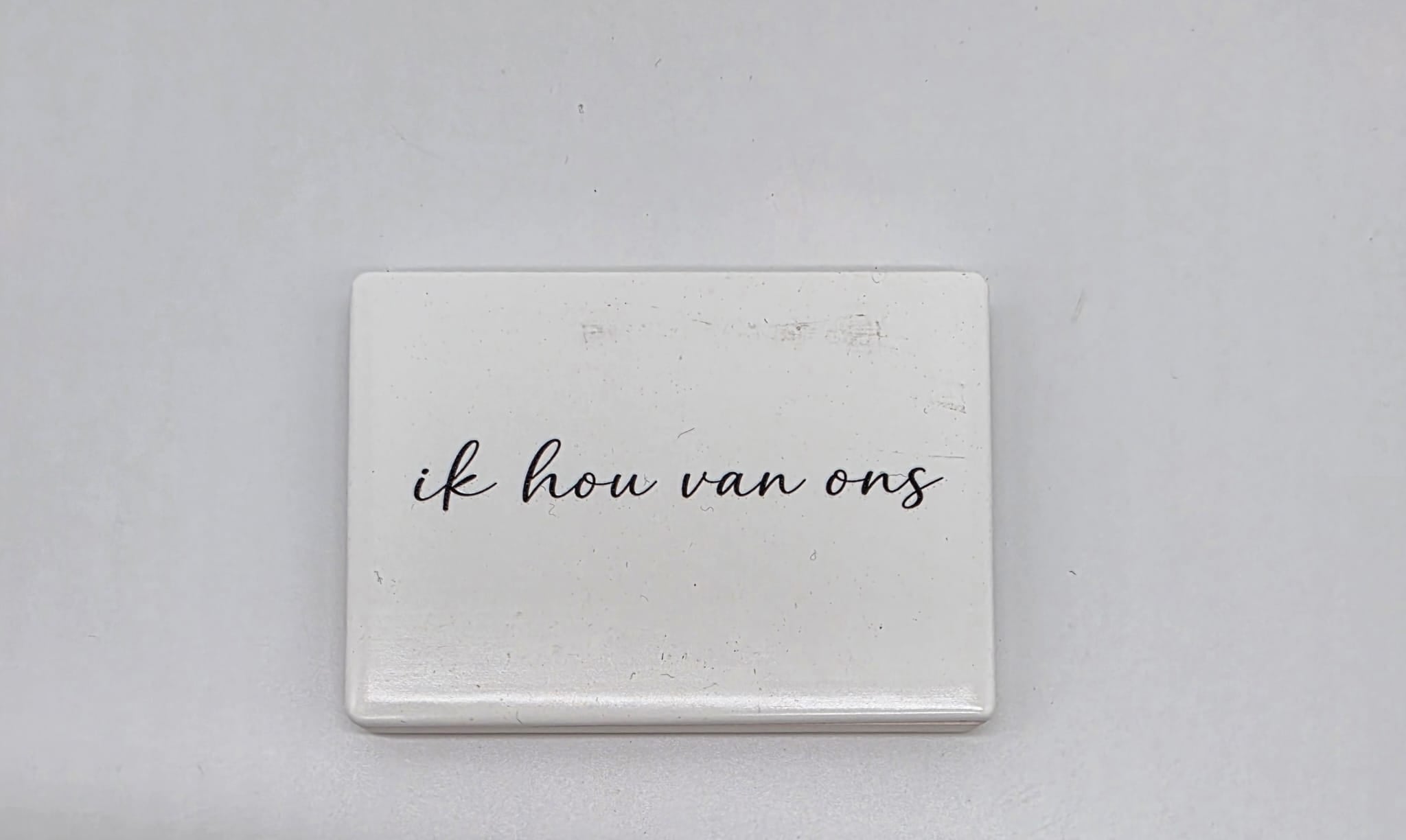 Keramische koelkastmagneet met de tekst Ik hou van ons op een witte achtergrond.