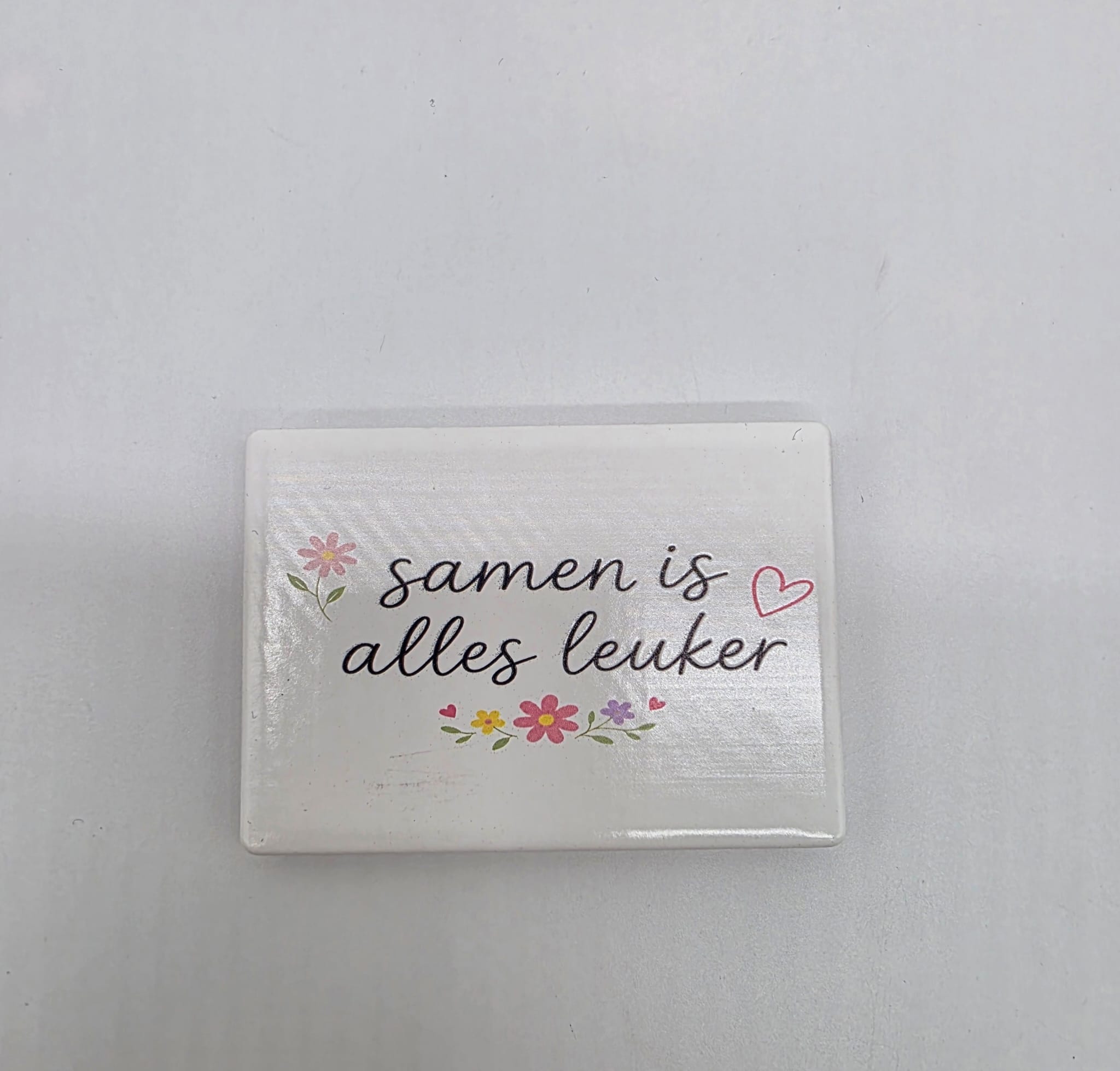 Keramische koelkastmagneet met de tekst Samen is alles leuker, bloemen en een hartje op een lichte achtergrond.