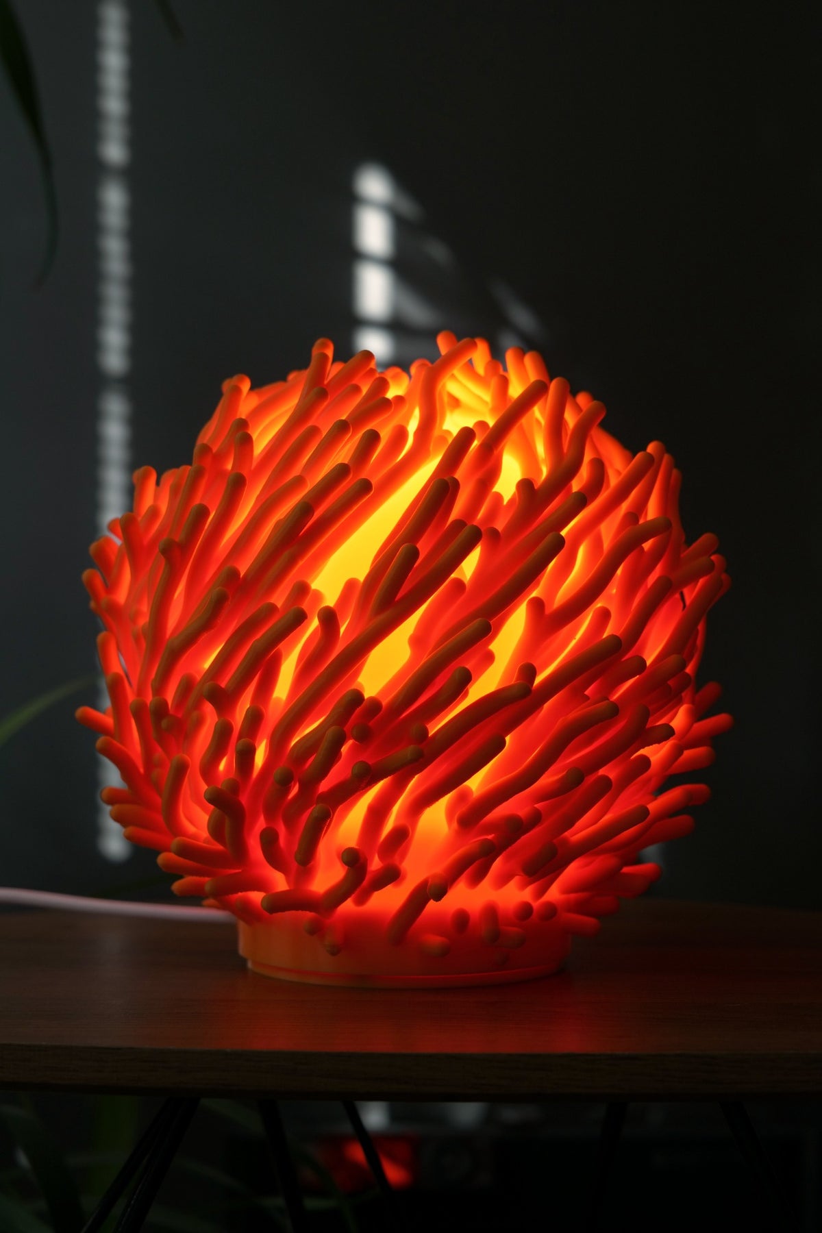 Rode Koraal design tafellamp ingeschakeld als warme sfeerlamp op tafel.
