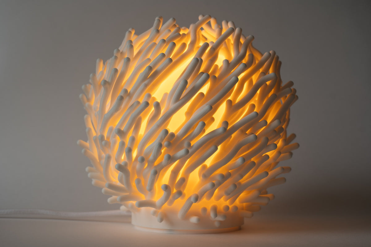 Witte Koraal organische design tafellamp ingeschakeld met warm sfeervol licht.