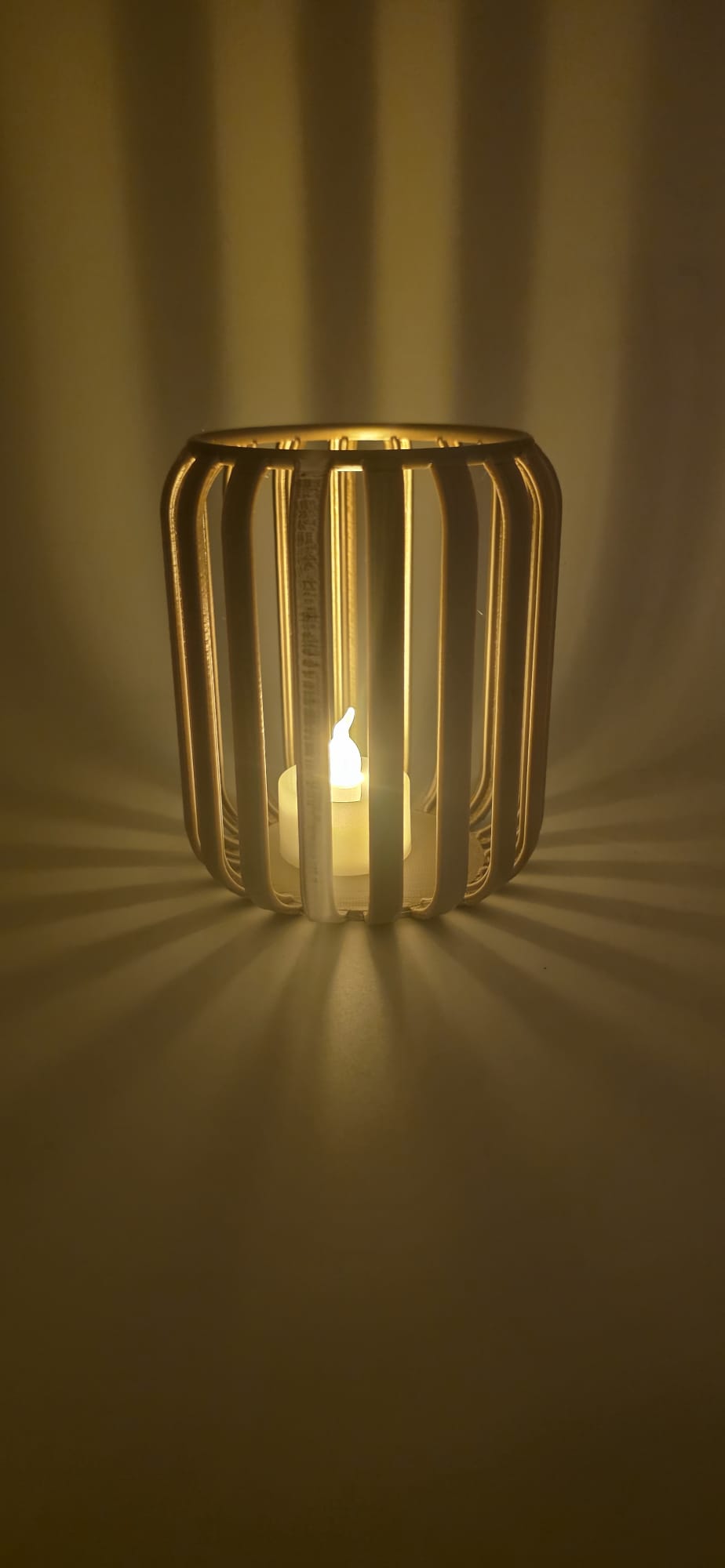 LED-theelichthouder met open ribstructuur en warm licht- en schaduwspel.