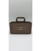 Bruine make-up organiser met handgreep en quilted patroon op lichte achtergrond.