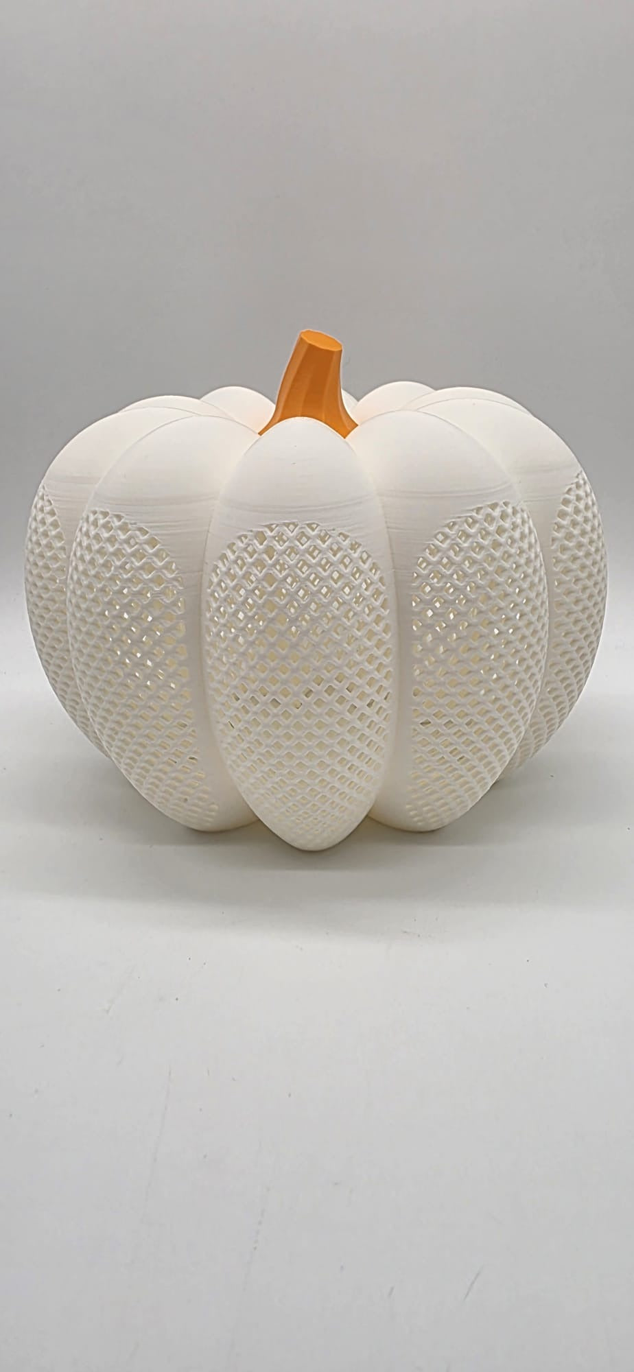 Witte decoratieve pompoen met open rasterstructuur.