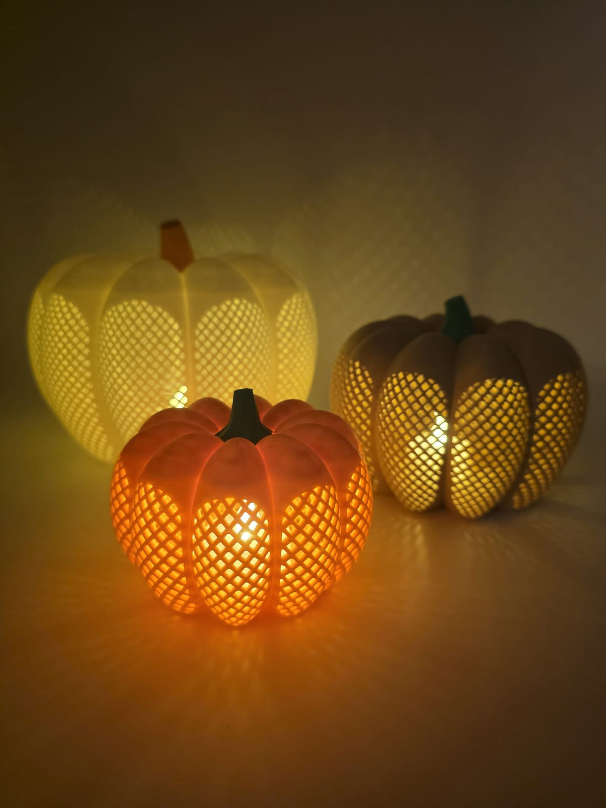 Drie verlichte pompoenen met LED-waxinelichtjes.