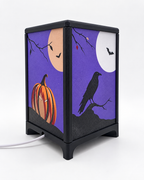 Uitgeschakelde Halloween-sfeerlamp met zwart frame en frontjes met een pompoen, raaf, maan en vleermuizen.