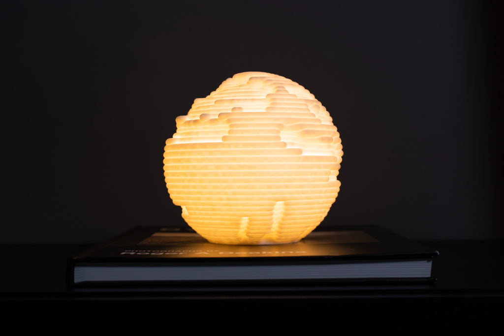 Strata mini sfeerlamp met warme LED-verlichting tegen een donkere achtergrond.