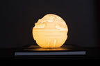 Strata mini sfeerlamp met warme LED-verlichting tegen een donkere achtergrond.