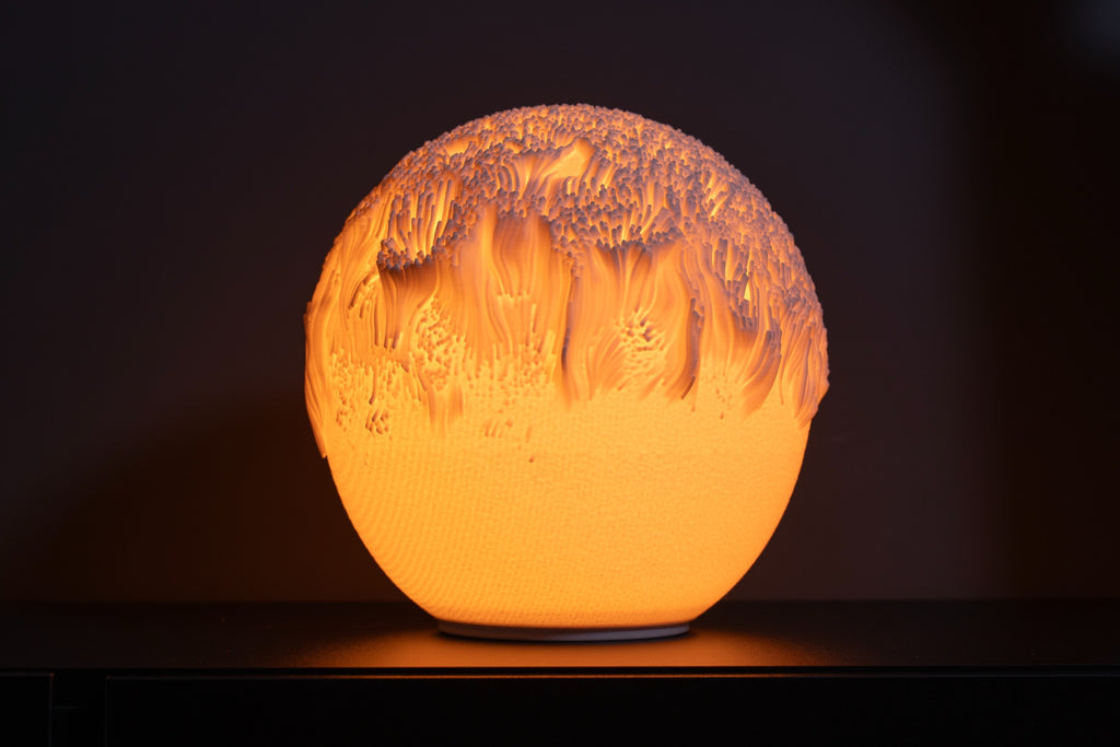 Tide design sfeerlamp brandend tegen een donkere achtergrond met sterk licht- en schaduwspel.
