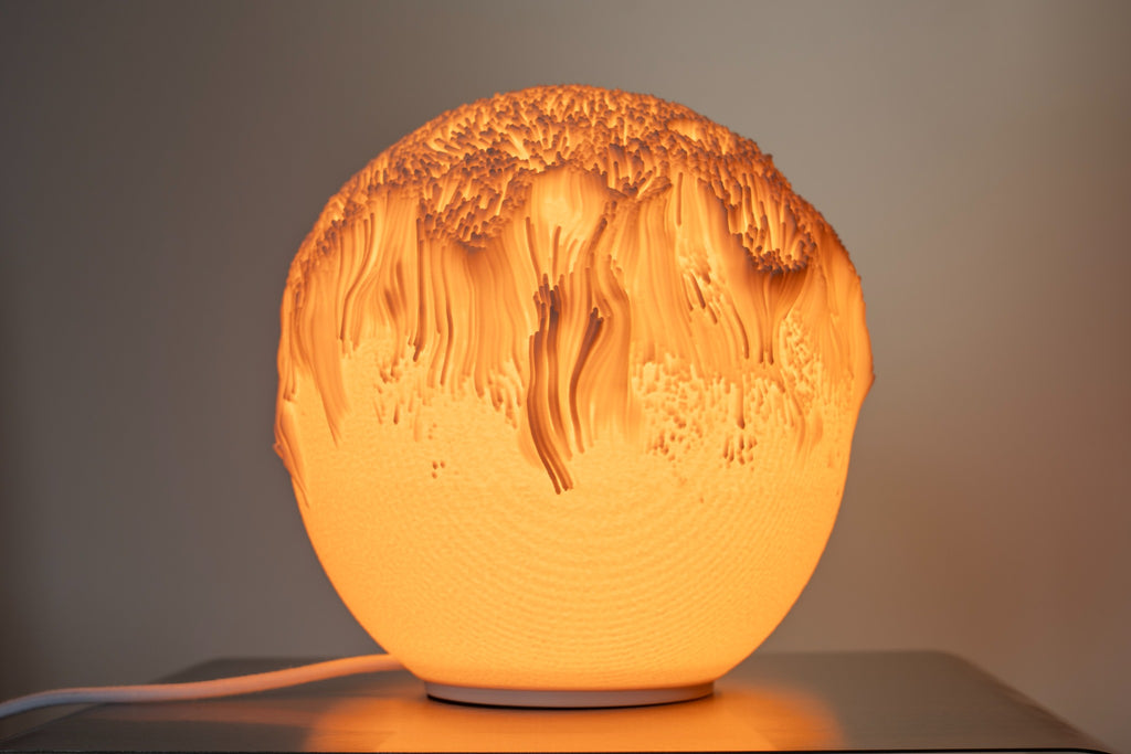 Tide tafellamp met gelaagd organisch reliëf en warme lichtgloed.