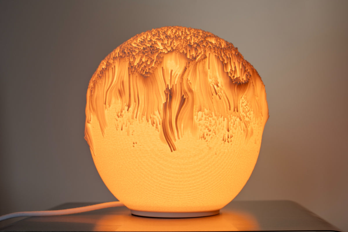 Tide tafellamp met gelaagd organisch reliëf en warme lichtgloed.