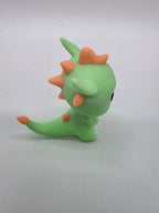 Zijaanzicht van de groene 3D-geprinte draak met oranje stekels en lange staart.
